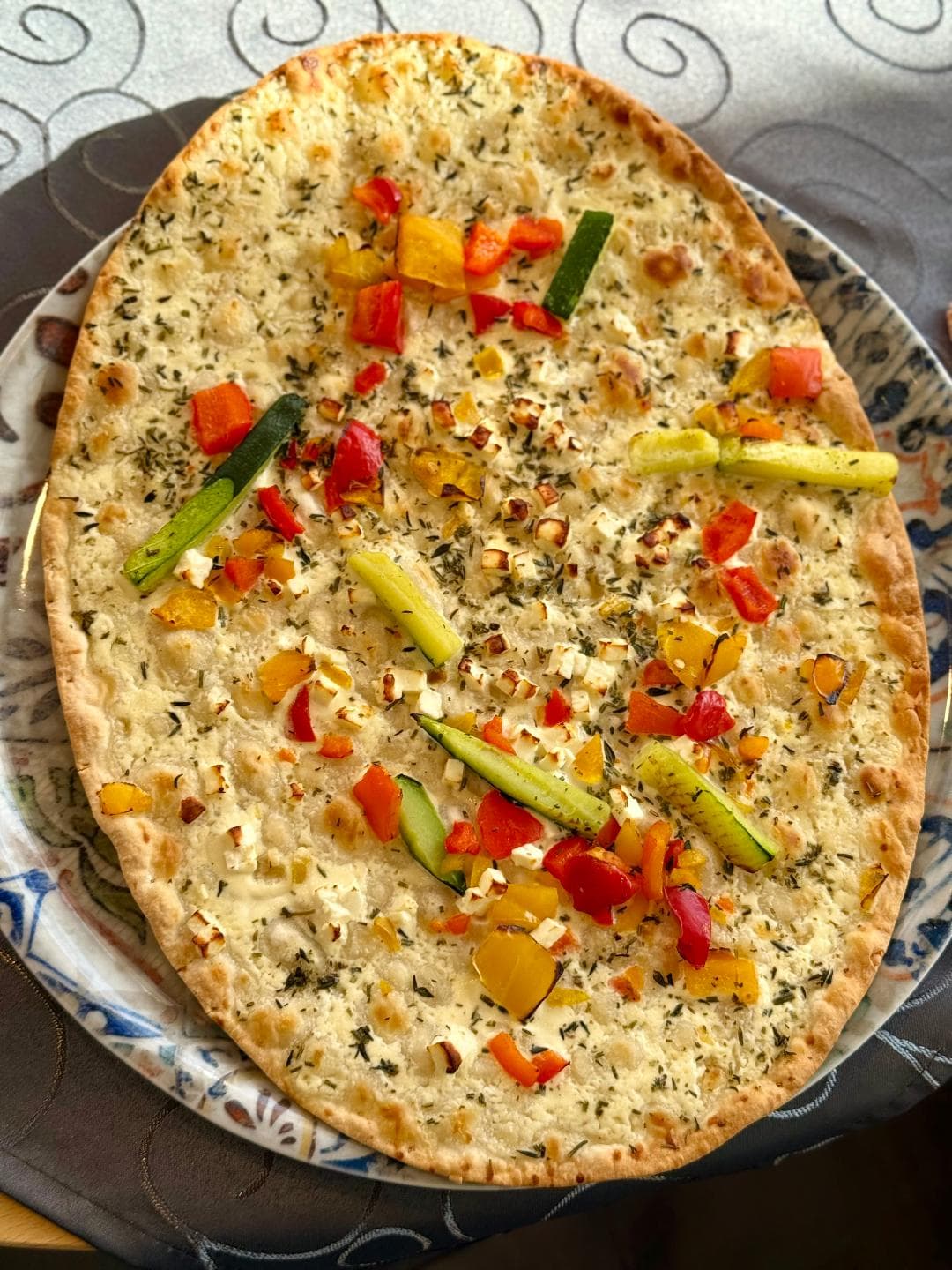 Crisp oven-baked tarte flambée topped with colourful peppers, zucchini and herbs at Zentrum Café Restaurant