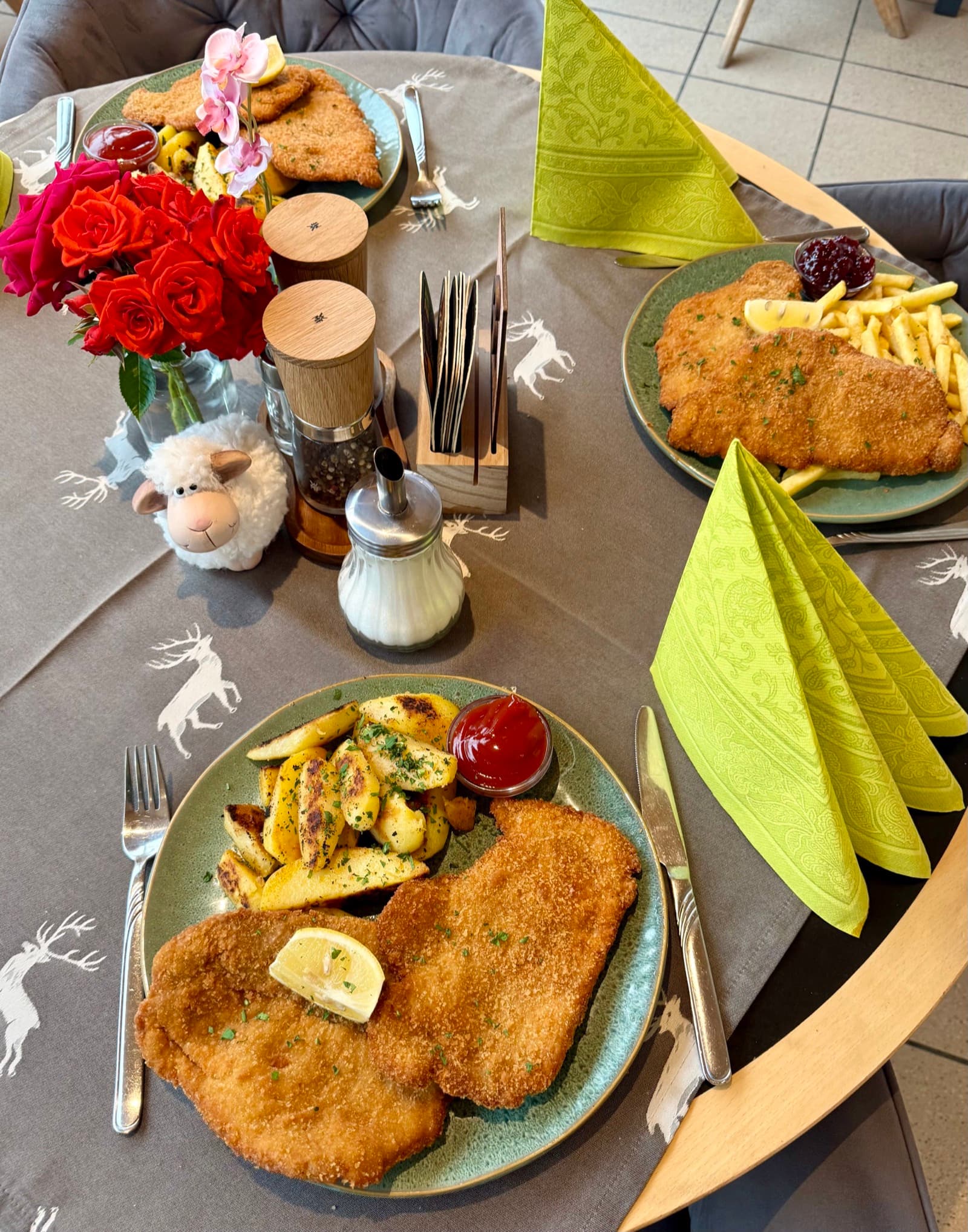 Golden Wiener Schnitzel with roast potatoes, fries, lemon and cranberries served on a decorated table at Zentrum Café Restaurant